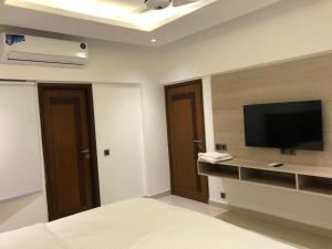 een slaapkamer met een flatscreen-tv aan de muur bij Hamsun Apart Hotel Clifton in Karachi
