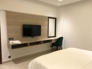 a bedroom with a flat screen tv on a wall at Hamsun Apart Hotel Clifton in Karachi