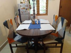 a dining room table with chairs and a refrigerator at Krishna Kuteera in Siddapur