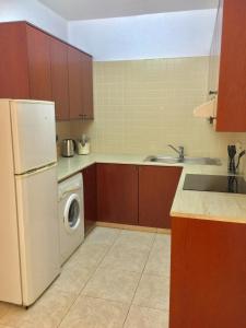 a kitchen with a white refrigerator and a washing machine at Cosy 2 bedroom apartment in Paphos