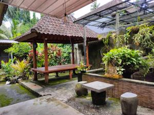 einen Pavillon mit einer Bank und einem Tisch im Garten in der Unterkunft Bale Bali Cottage 2 in Ubud