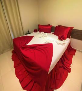uma cama grande com lençóis vermelhos e brancos e almofadas vermelhas em Angra Praia Hotel em Fortaleza