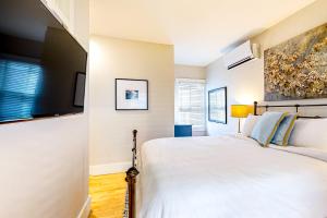 1 dormitorio con 1 cama blanca y TV de pantalla plana en The Heart of the West End #3 & #4, en Portland