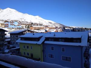 uma cidade com edifícios cobertos de neve e uma montanha em Mountain Shelter em Passo del Tonale