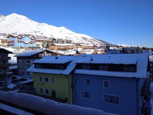 a city with snow covered buildings and a mountain at Mountain Shelter in Passo del Tonale