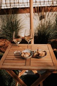 una mesa de madera con dos copas de vino y comida. en Chez Brens - Maison d'hôtes à La Hume, en Gujan-Mestras
