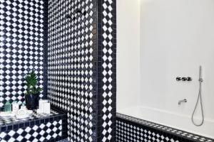 a bathroom with a black and white tiled wall at Katikies Garden Santorini - The Leading Hotels Of The World in Fira