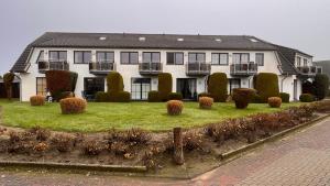 a large white house with a yard with bushes at Ferienwohnung am Kormoranweg in Dorum-Neufeld