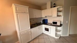 a small kitchen with white cabinets and a microwave at Ferienwohnung am Kormoranweg in Dorum-Neufeld