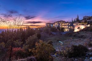 a house on a hill with a sunset in the background at Snowglory Boutique Hotel in Arachova