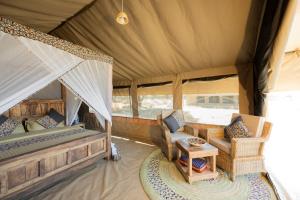 1 dormitorio en una tienda de campaña con 1 cama y sillas en Africa Safari South Serengeti Ndutu Ngorongoro en Sinoni