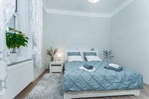 een witte slaapkamer met een blauw bed en een raam bij Alla Prague Apartment in Praag