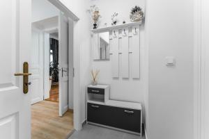 a hallway with white walls and a white door with a shelf at Alla Prague Apartment in Prague