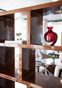 a red vase sitting on top of a wooden shelf at Cosmo Hotel Torri in Vimercate