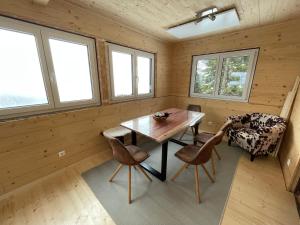 uma sala de jantar com mesa, cadeiras e janelas em Stubihuettn em Sonnenalpe Nassfeld