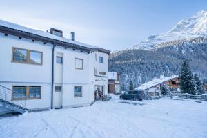 a building with a car parked next to a snow covered mountain at Haus Lena in Solda