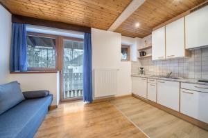 a kitchen with white cabinets and a blue couch at Haus Lena in Solda