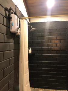ein Badezimmer mit einer Backsteinwand und einem Duschvorhang in der Unterkunft High-end Holiday Cabin - Tungurahua Hot Springs in Baños