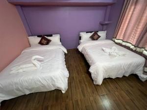 ein Zimmer mit 2 Betten mit Schwänen darauf in der Unterkunft Old House Villa in Sauraha