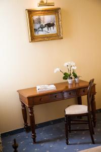 un bureau avec un vase de fleurs et une photo sur le mur dans l'établissement Cosmo Hotel Torri, à Vimercate