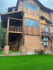 a brick building with a balcony and green grass at Floor river view in Cat Tien