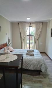 a bedroom with a bed and a table and a window at Loft/Apart Michel Iguazu in Puerto Iguazú
