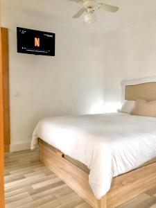 1 dormitorio con 1 cama y TV en la pared en Valdelagrana vistas al mar, piscinas primera linea cadiz en El Puerto de Santa María
