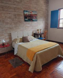 um quarto com uma cama grande e piso em madeira em Pousada Solar das Oliveiras em Ouro Preto