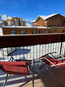 ein Paar Stühle auf einem Balkon mit schneebedeckten Bergen in der Unterkunft Cosy and Lovely Unit in Val Thorens
