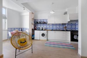 a kitchen with white cabinets and a chair at The Beach Place in Costa da Caparica
