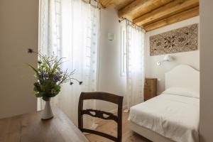a bedroom with a table and a bed and a vase with flowers at Le Pervinche in Refrontolo
