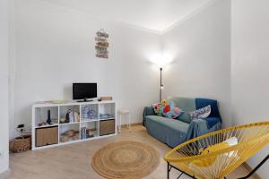 a living room with a blue couch and a tv at The Beach Place in Costa da Caparica