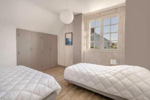 a white bedroom with a bed and a window at Séjour pour 11 - Jardin - Arzon in Arzon
