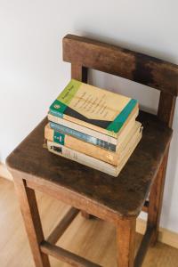 a stack of books sitting on top of a wooden chair at Campanha Apartment By Porto Stories in Porto