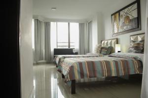 a bedroom with two beds and a chair and a window at Edificio Kelly in Cali