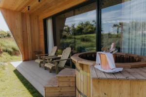 a woman sitting on a deck next to a hot tub at The Garden Rooms in Chathill