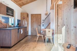 cocina con paredes de madera, mesa y sillas en Guntschöllerhof Rotwand, en Fiè