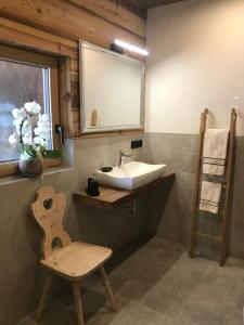a bathroom with a sink and a chair and a mirror at Grieshof am Pühel in Valle Di Casies