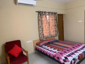 a bedroom with a bed and a chair and a window at Sunil Residency in Coimbatore