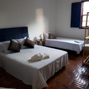 duas camas num quarto com lençóis brancos em Pousada Solar das Oliveiras em Ouro Preto