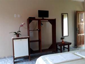 a room with a bed and a tv on the wall at Pousada Bromélias - Suítes e Aptos in Nova Viçosa