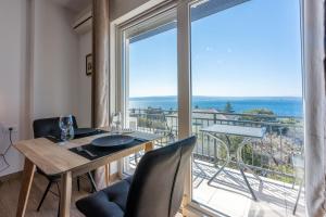 a dining room with a table and a large window at Apartments Domino R in Dramalj