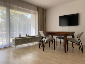 ein Wohnzimmer mit einem Tisch, Stühlen und einem TV in der Unterkunft Pension am Waldrand in Karlsbad