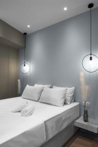 ein weißes Schlafzimmer mit einem großen weißen Bett mit zwei Lichtern in der Unterkunft Bliss Apartments, The Luxury Suites in Thessaloniki