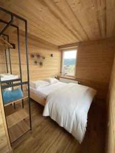 ein Schlafzimmer in einer Holzhütte mit einem Bett und einem Fenster in der Unterkunft Les Chalets Bambi & Jacuzzi privatif in La Bresse