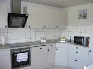 cocina con armarios blancos y microondas en Petersen Uwe, en Großenwiehe