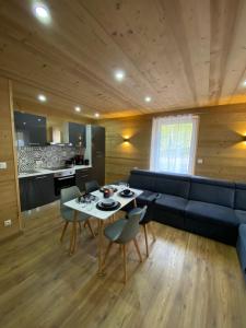 ein Wohnzimmer mit einem blauen Sofa, einem Tisch und Stühlen in der Unterkunft Les Chalets Bambi & Jacuzzi privatif in La Bresse