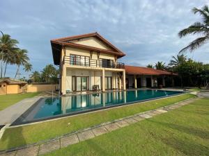 a villa with a swimming pool in front of a house at Reef Bungalow Hotel in Pamunugama