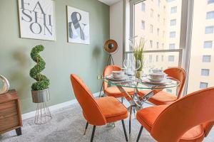 a dining room with orange chairs and a glass table at Luxury Apartment - City Centre - Free Parking, Fast Wifi, Sky TV and Netflix by Yoko Property in Milton Keynes
