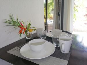 una mesa negra con platos blancos y gafas. en Las Perlitas Rentals Playa Samara, en Sámara